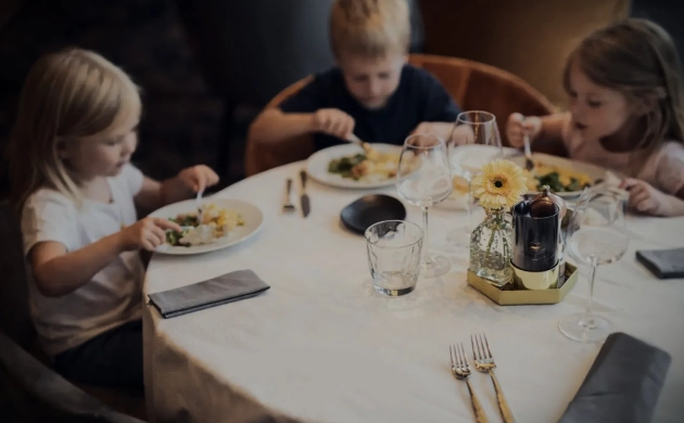 Trois enfants dégustent un repas autour d'une table dressée