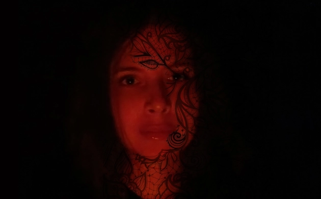 Sur un fond noir, le visage d’une femme apparaît sous un filtre