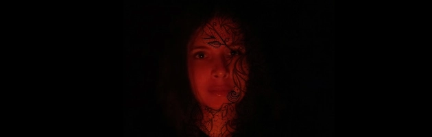 Sur un fond noir, le visage d’une femme apparaît sous un filtre