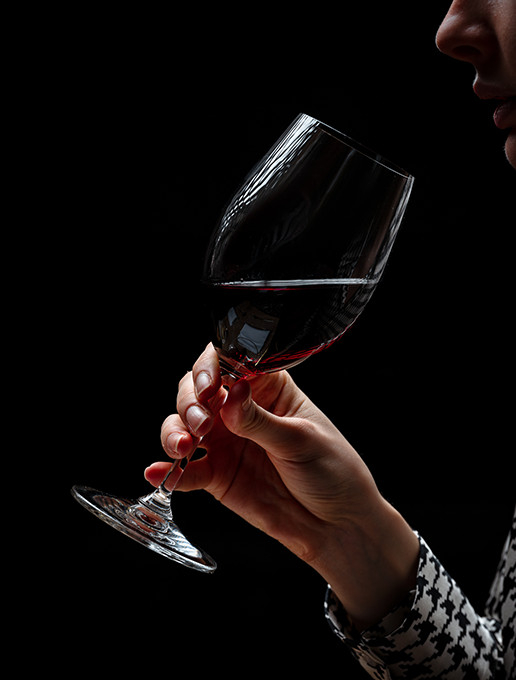 A young woman enjoying a glass of wine in a cozy atmosphere to celebrate Christmas at the Dans le Noir ? restaurant