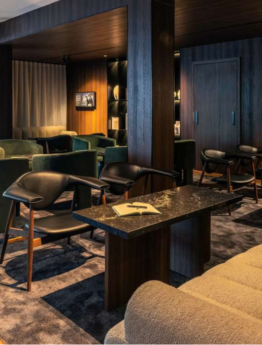 Refined lounge at the Novotel Luxembourg Kirchberg with wooden and velvet furniture, soft lighting and a cozy atmosphere for a moment of relaxation.