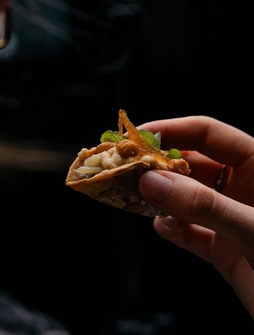 Gros plan d'un amuse-bouche sophistiquée tenu dans une main.