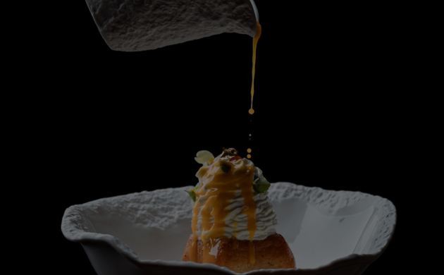 Dessert gastronomique servi dans un bol blanc, nappé d’une sauce versée à la dernière minute, présenté de manière élégante sur fond noir